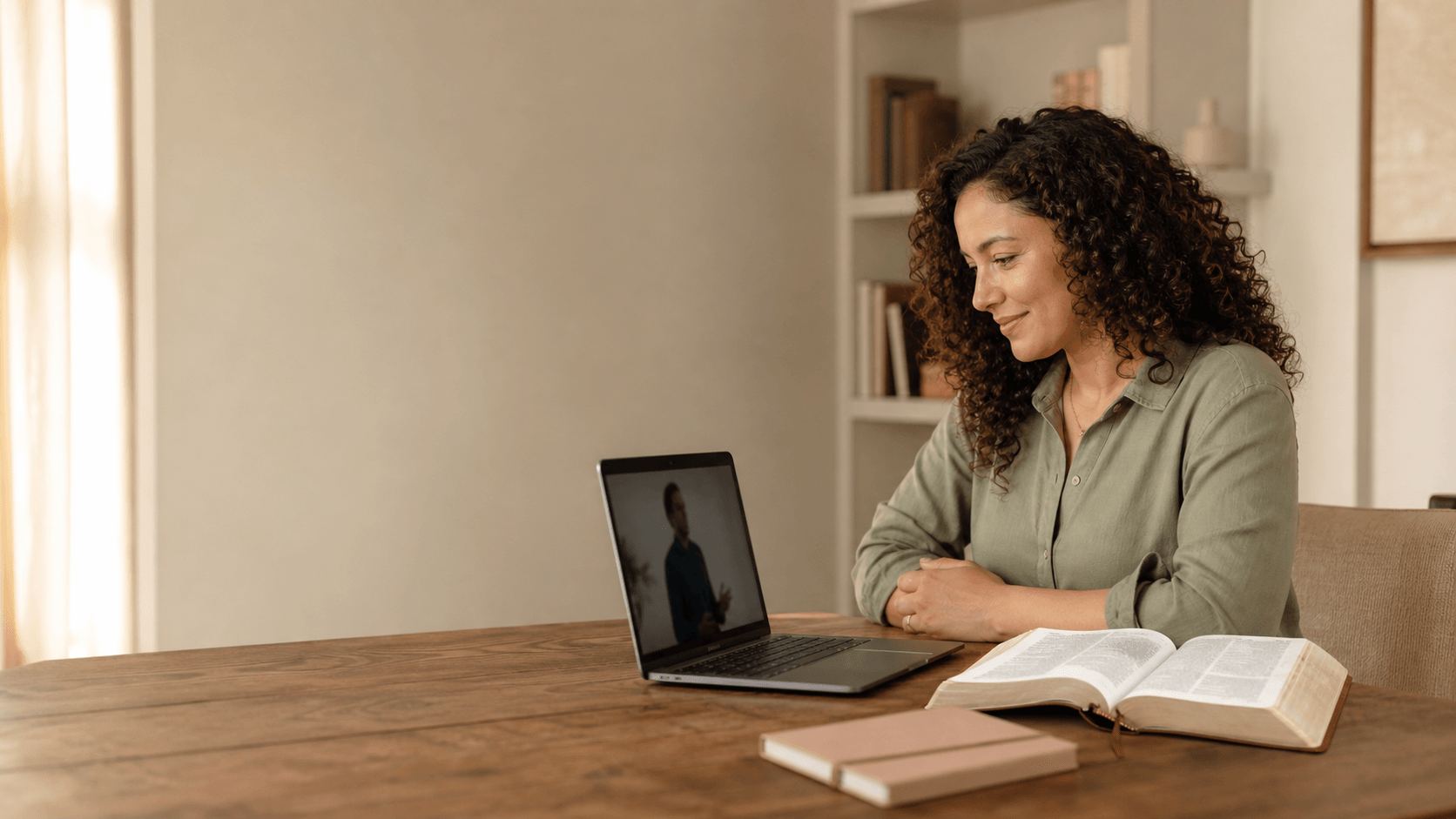 A woman watching a video devotional beside an open Bible
